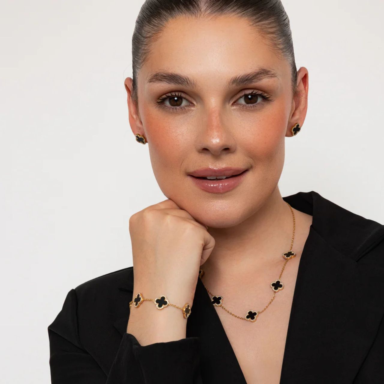 These Knight & Day Estella stud earrings feature an elegant clover design, enhanced with glossy black resin and sparkling crystal accents.