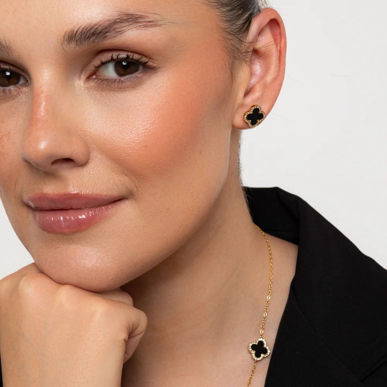 These Knight & Day Estella stud earrings feature an elegant clover design, enhanced with glossy black resin and sparkling crystal accents.