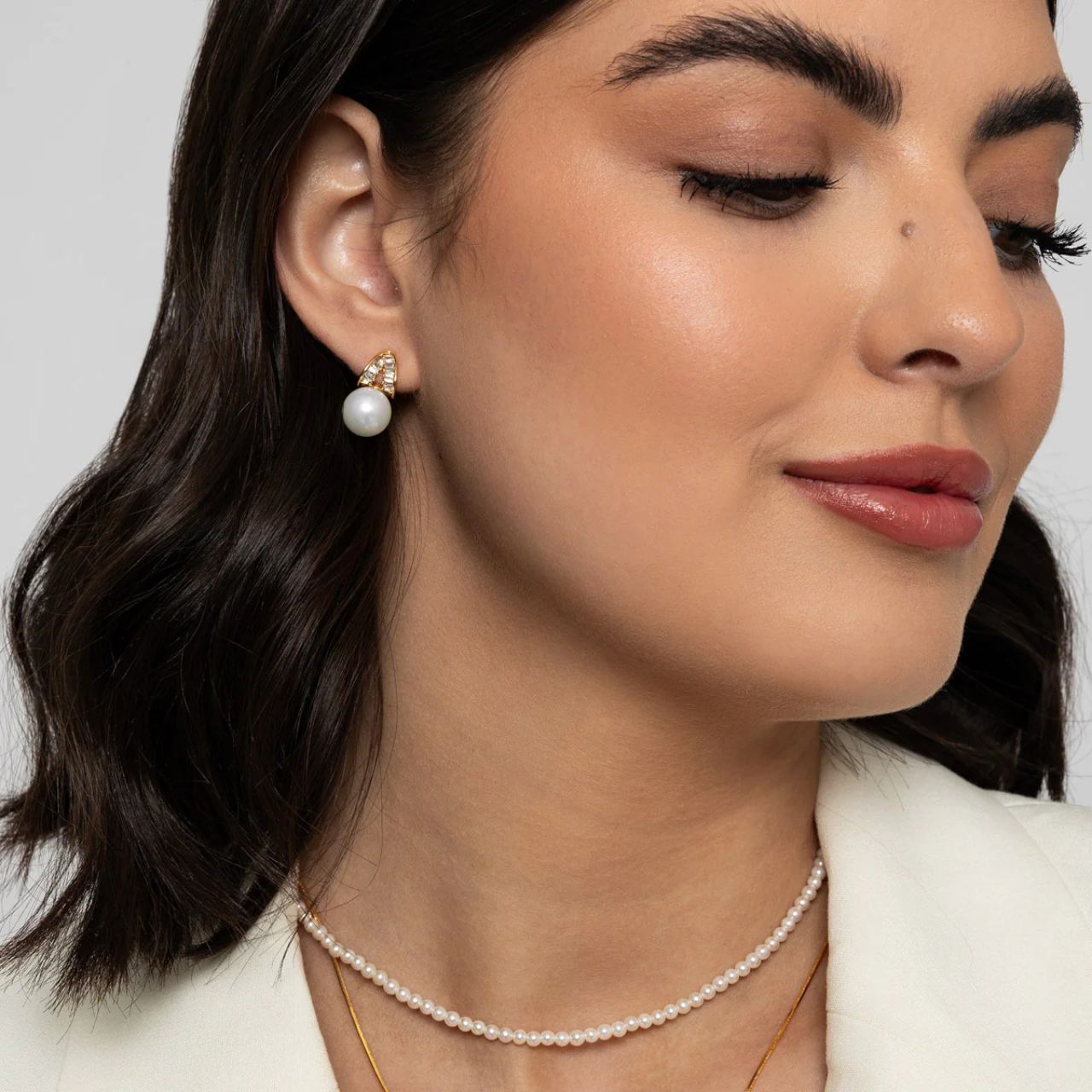 Beautiful faux pearl earrings embellished with CZ stones in baguette cut. Post fastening. 18K gold plating.