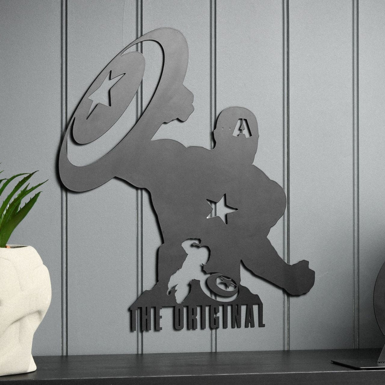 Infuse your space with a touch of superhero allure with our Marvel The Avengers Captain America Wall Plaque. This striking piece features a silhouetted figure holding a star-emblazoned shield, beneath the bold declaration: "THE ORIGINAL".