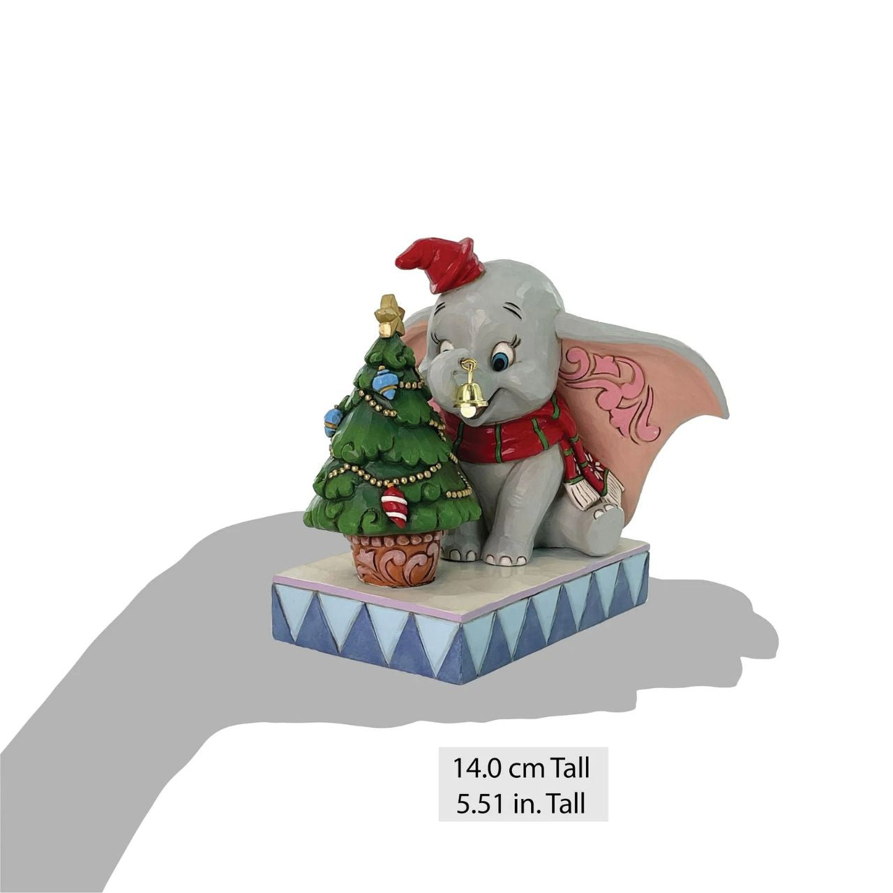 In this heartwarming Jim Shore scene, Dumbo is festively dressed in a red coat and hat as he joyfully decorates a miniature Christmas tree with a real working bell in his trunk. Capture the spirit of the season with Dumbo's playful spirit.