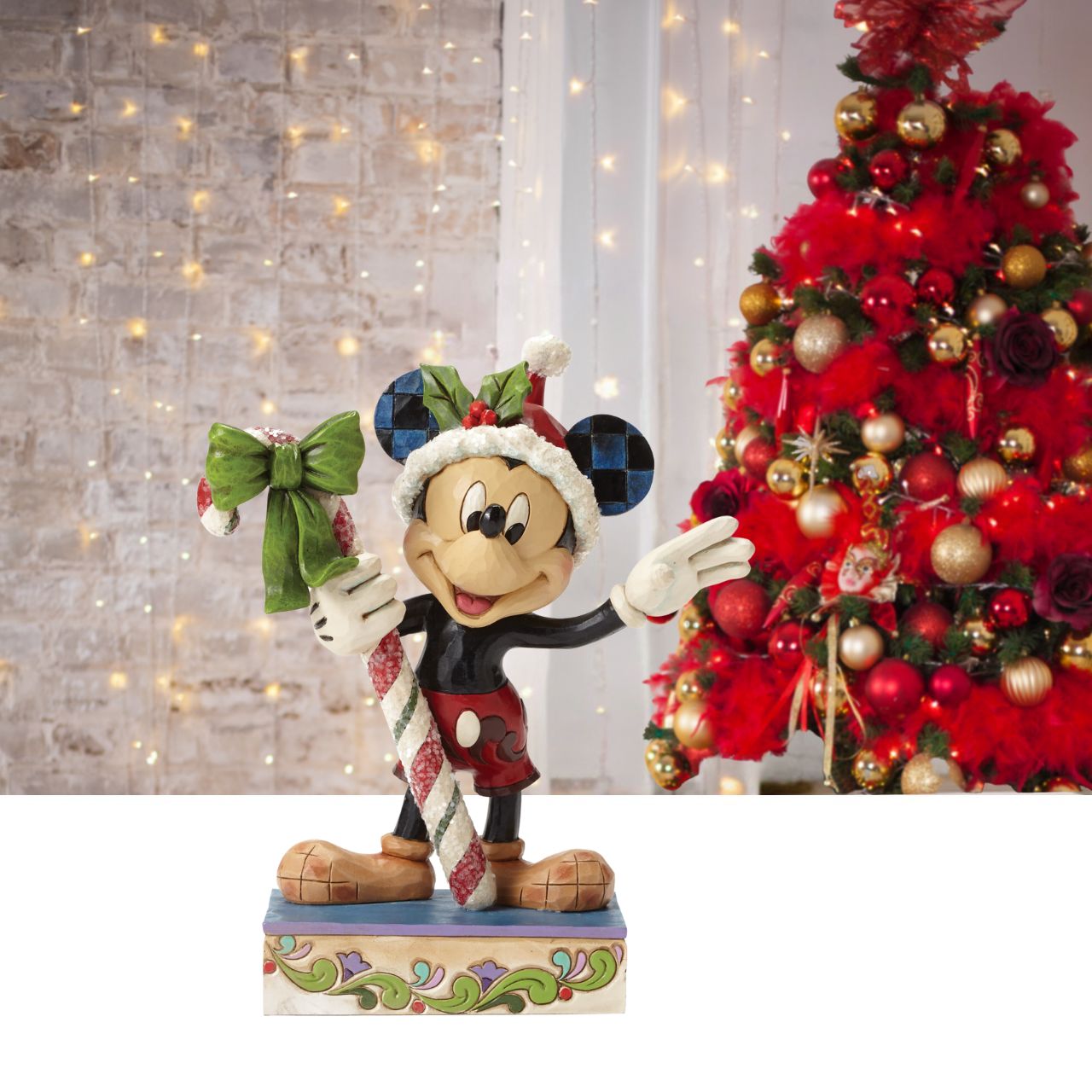Disney Mickey Mouse Candy Cane Figurine  "Sweet Greetings" A jolly Mickey Mouse brings a gift of sugar coated candy in this delightful Christmas design from the artistry of Jim Shore. Beautifully handcrafted, this eye-catching piece features the classic Disney character decorated in Jim's unique folk art style. The figurine is made from cast stone.