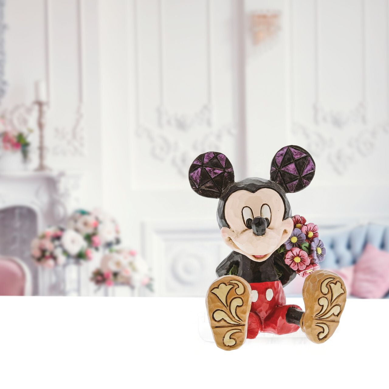 Mickey Mouse with Flowers by Jim Shore  Beautifully handcrafted and delightfully decorated in time-honoured folk art motifs, Jim Shore's charming miniatures capture the essence of beloved Disney characters. Mickey hides a bouquet behind his back in this whimsical, playfully romantic scene. Great for Valentines day, birthdays and just because days.