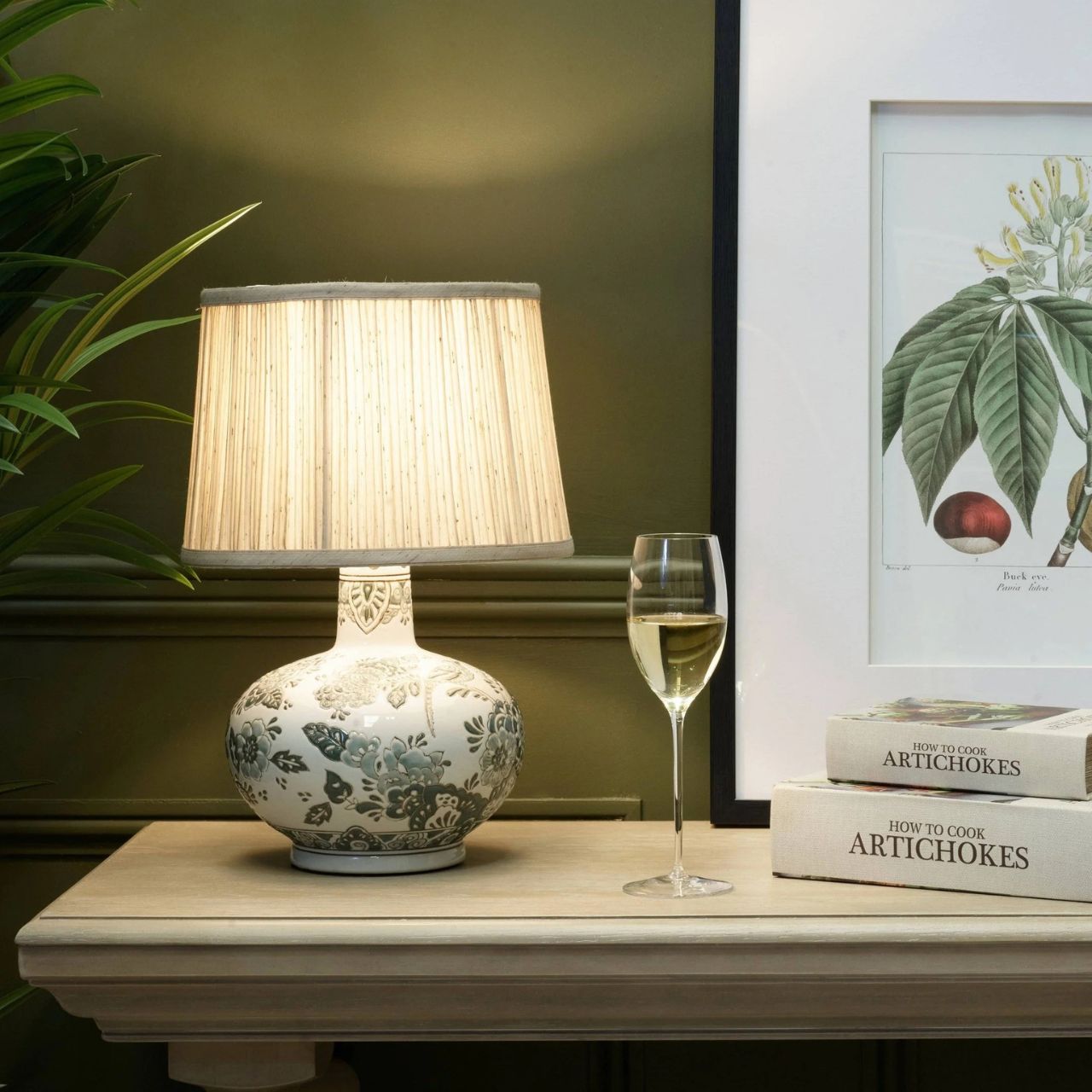 The Hannah Lamp offers a soft and elegant take on floral ceramic design. Its rounded base features a delicate botanical pattern in gentle neutral tones, creating a calm and refined look. Paired with a pleated shade, it casts a warm, soothing glow that enhances its subtle detailing.