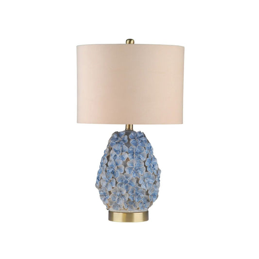 The Olivia Lamp is a charming piece inspired by delicate floral forms. Its rounded ceramic base features softly raised blossoms in gentle blue tones, creating texture and a subtle romantic feel. Finished with a neutral shade, it casts a warm, inviting glow.