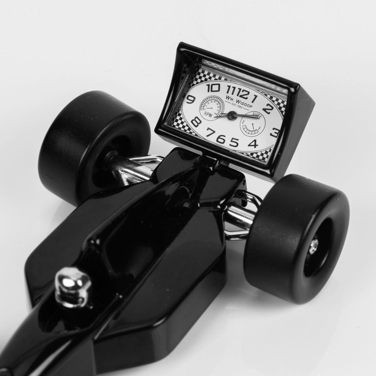 Miniature Clock - Black Racing Car  A delightful, retro inspired die-cast black miniature racing car clock from WILLIAM WIDDOP. With superb attention to detail this makes a wonderful gift for the desk of a friend or loved one with a passion for the motor racing or formula 1. Complete with moving steering wheel and tyres.