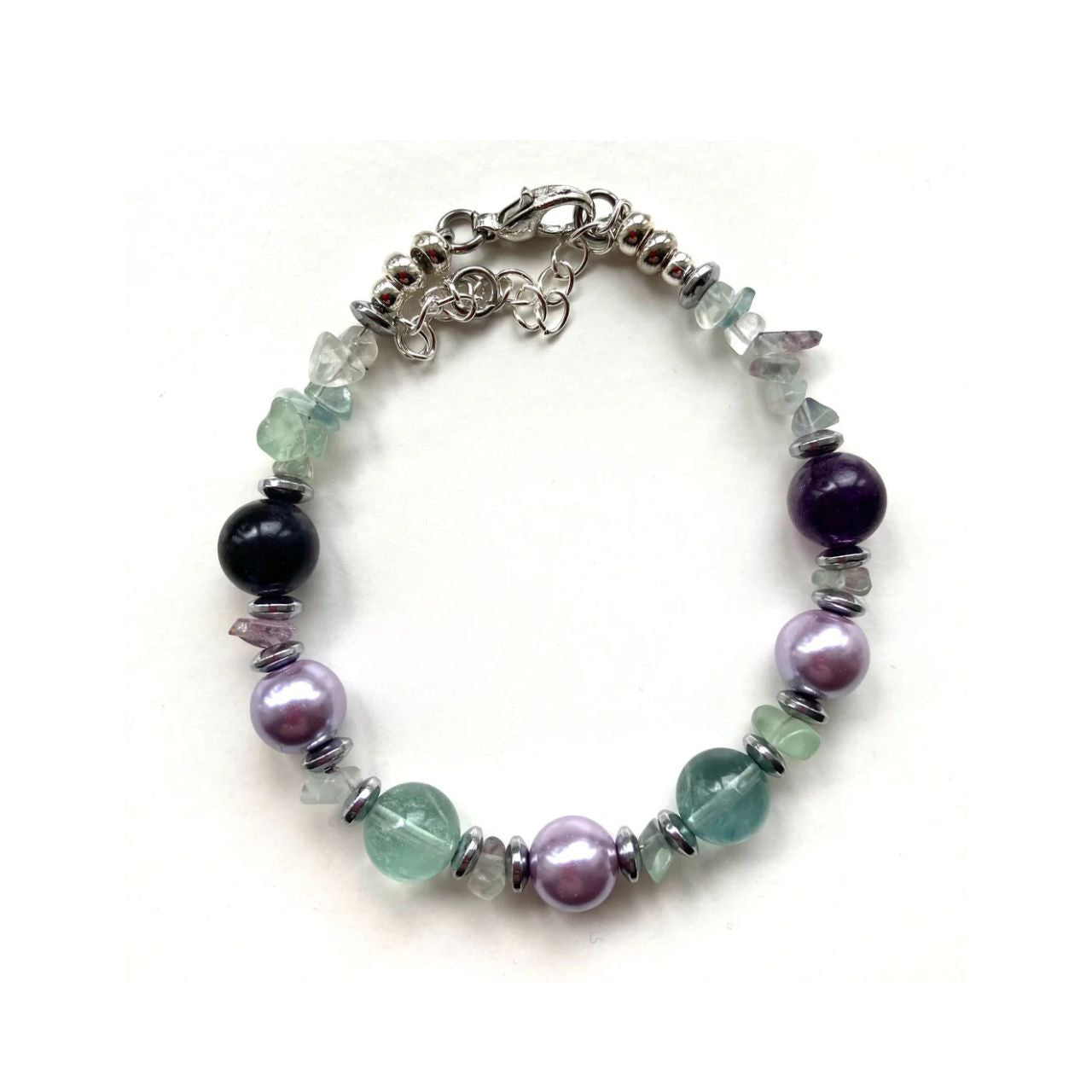 In this bracelet we have green and purple Flourite gemstone chips and round beads combined with lilac Glass Pearls and silver plated Hematite gemstone rondelles.