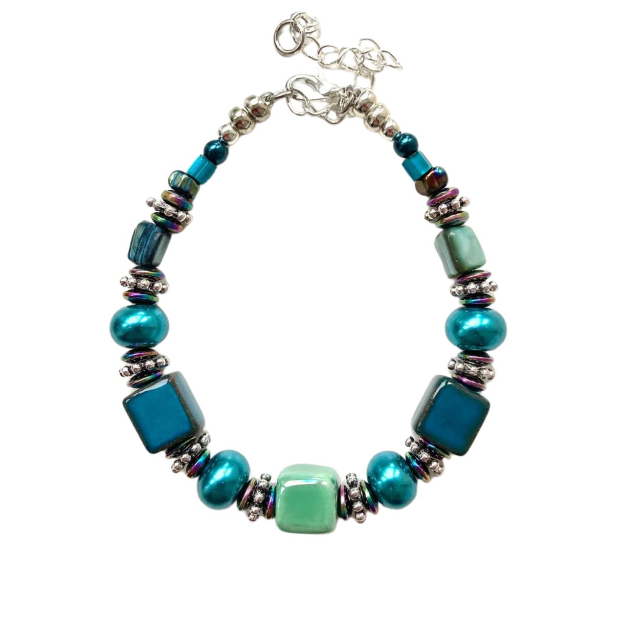 This bracelet features handmade Ceramic cubes in seagreen and teal with Turquoise Pearl Rondelles, teal coloured Shell beads, tiny iridescent Hematite gemstone rondelles and decorative silver-toned elements.