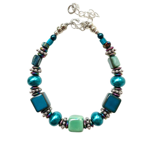 This bracelet features handmade Ceramic cubes in seagreen and teal with Turquoise Pearl Rondelles, teal coloured Shell beads, tiny iridescent Hematite gemstone rondelles and decorative silver-toned elements.