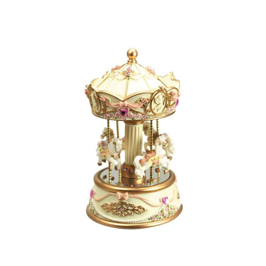 Music box carousel beige. The pretty cream coloured carousel is decorated with pink glass stones and bows. The base is decorated with golden ornaments. 4 richly adorned carousel horses are ready to go. When turning the roof, the mechanism is wound up an the carousel on the base turns to the melody “Minuet Mozart” plays.