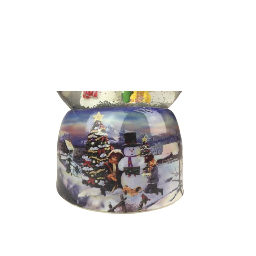 Musicbox World Snow Globe Snowman & Dog  Snow globe with snowman. In the ball filled with glitter and snow, a man stands with his dog and looks at the tall smiling snowman standing close to a tree. The base is painted with a snowy wintery village landscape. By winding up the mechanical movement with the disc, the music box turns on the disc to the melody “Silent Night”. 