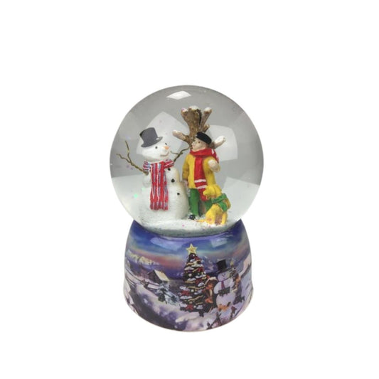Musicbox World Snow Globe Snowman & Dog  Snow globe with snowman. In the ball filled with glitter and snow, a man stands with his dog and looks at the tall smiling snowman standing close to a tree. The base is painted with a snowy wintery village landscape. By winding up the mechanical movement with the disc, the music box turns on the disc to the melody “Silent Night”. 