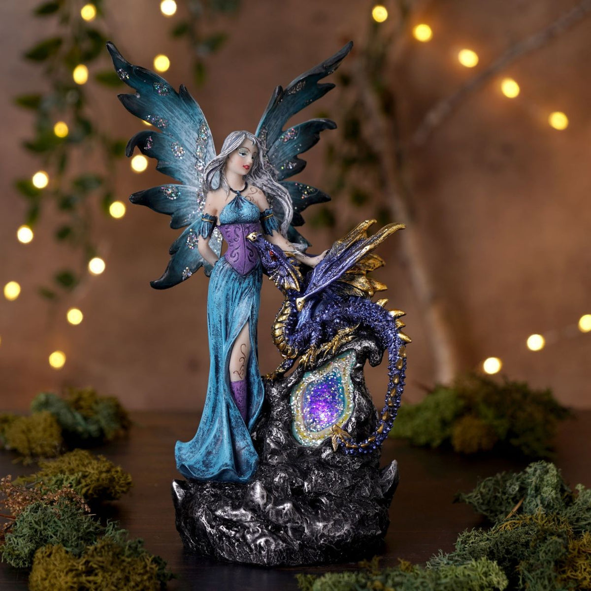 Mystic Legends LED Fairies with Dragon Red & Blue 21cm is a captivating pair of fantasy ornaments, designed to bring enchantment and drama to any display. Each piece features a beautifully sculpted fairy standing alongside a detailed dragon companion, positioned on a rugged rock-style base for a striking and immersive composition.