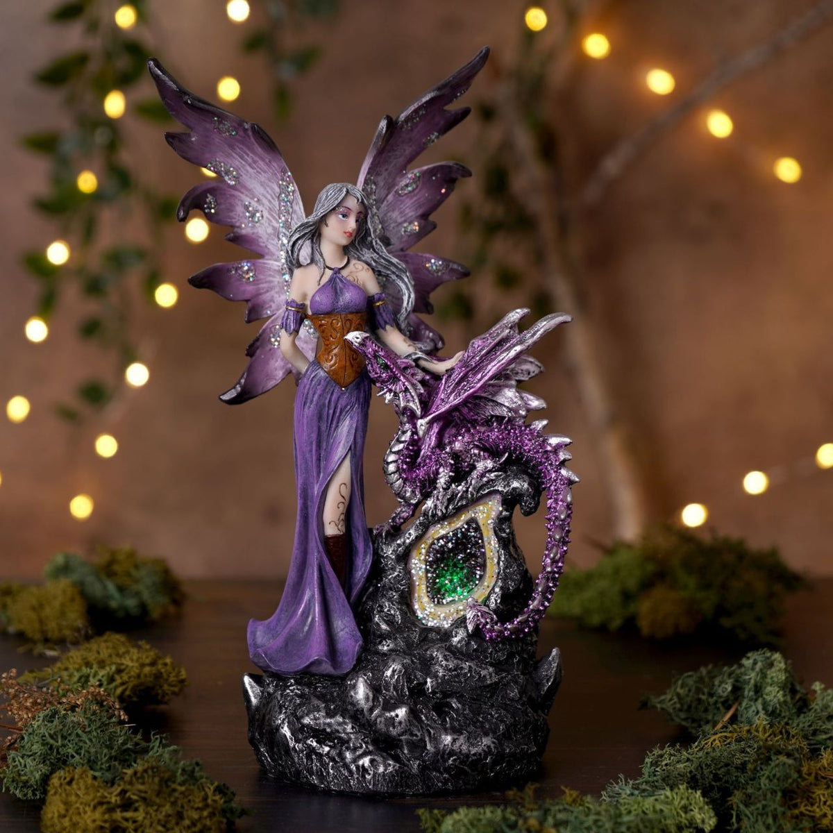 Mystic Legends LED Fairies with Dragon Green & Purple 21cm is a mesmerising pair of fantasy ornaments, designed to bring enchantment and rich colour to any display. Each piece features a beautifully sculpted fairy accompanied by a detailed dragon companion, standing atop a rugged rock-style base that enhances the sense of storytelling and depth.