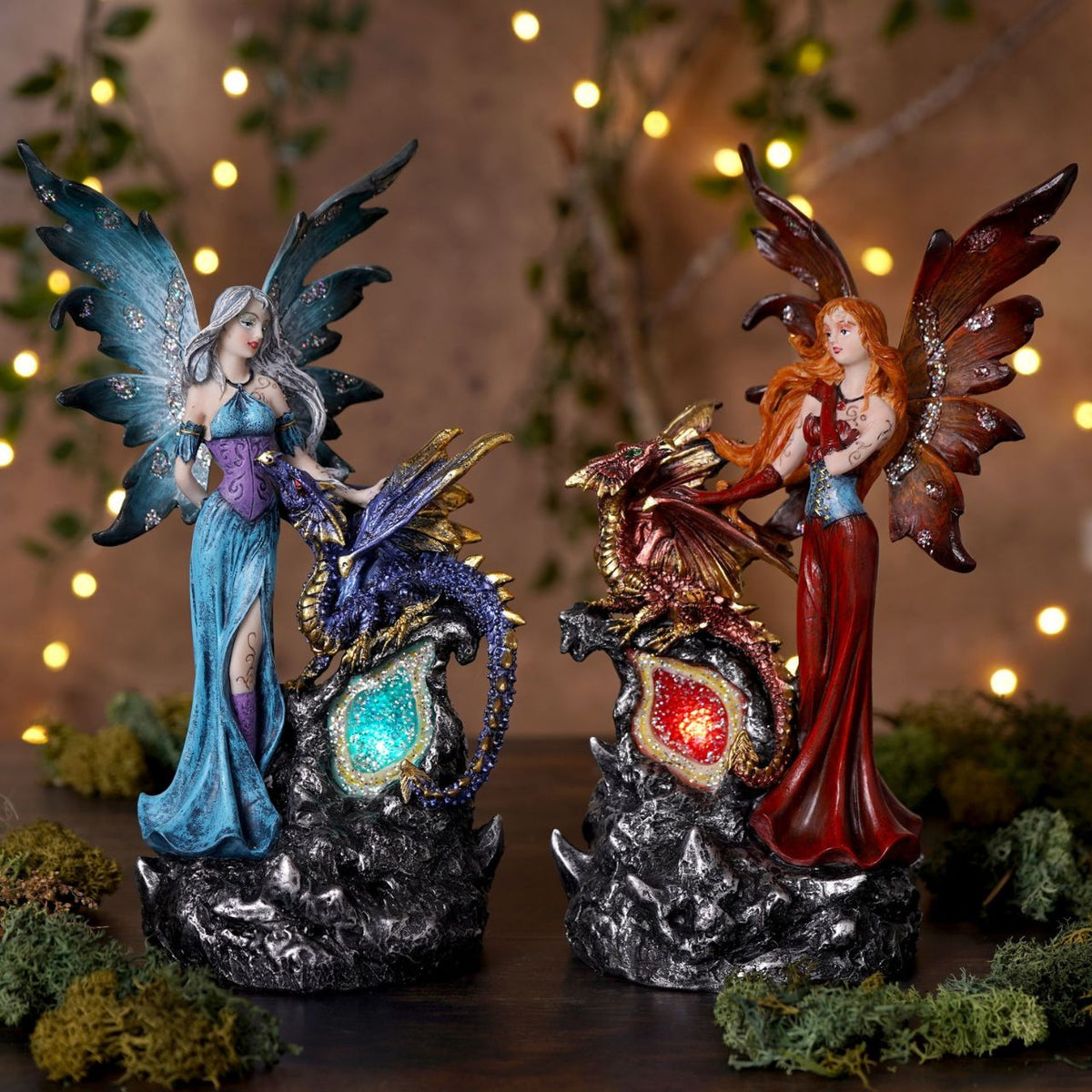 Mystic Legends LED Fairies with Dragon Red & Blue 21cm is a captivating pair of fantasy ornaments, designed to bring enchantment and drama to any display. Each piece features a beautifully sculpted fairy standing alongside a detailed dragon companion, positioned on a rugged rock-style base for a striking and immersive composition.