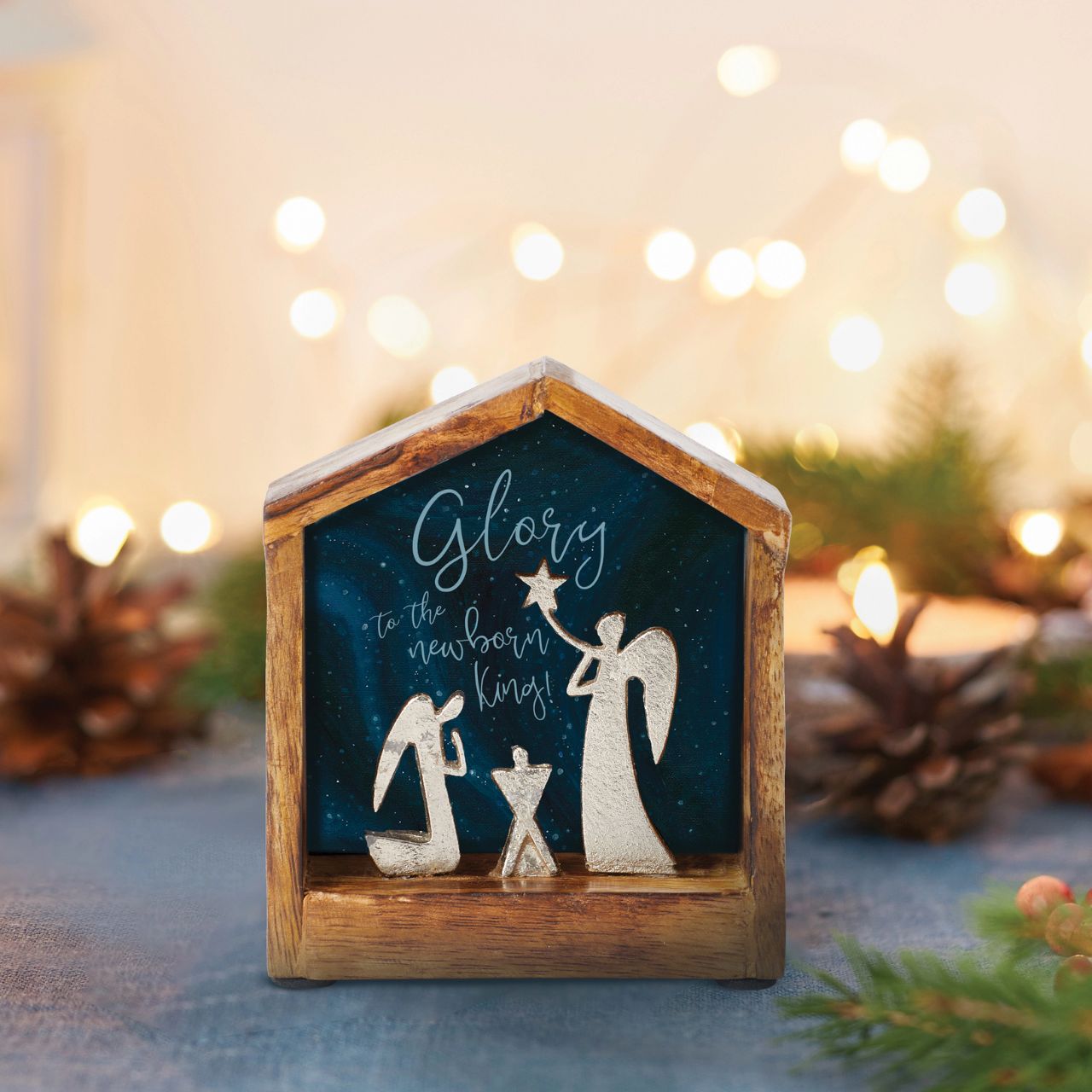 Artist, Wendy Wiinanen, crafts memorable and miniature traditional Christmas moments from mango wood and aluminium. This enchanting display places two angels in a wooden stable peering over a cradle.