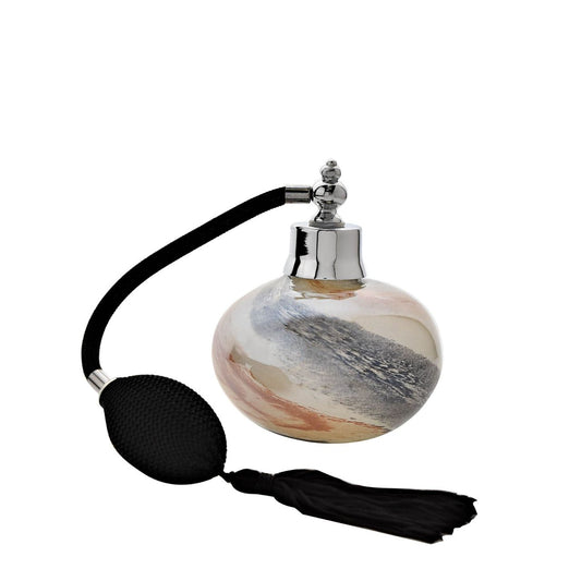 The round, glass bottle showcases a stunning marbled effect with swirls of black and gold. Attached to the bottle is a traditional perfume pump, complete with tassel and silver metal dispenser.