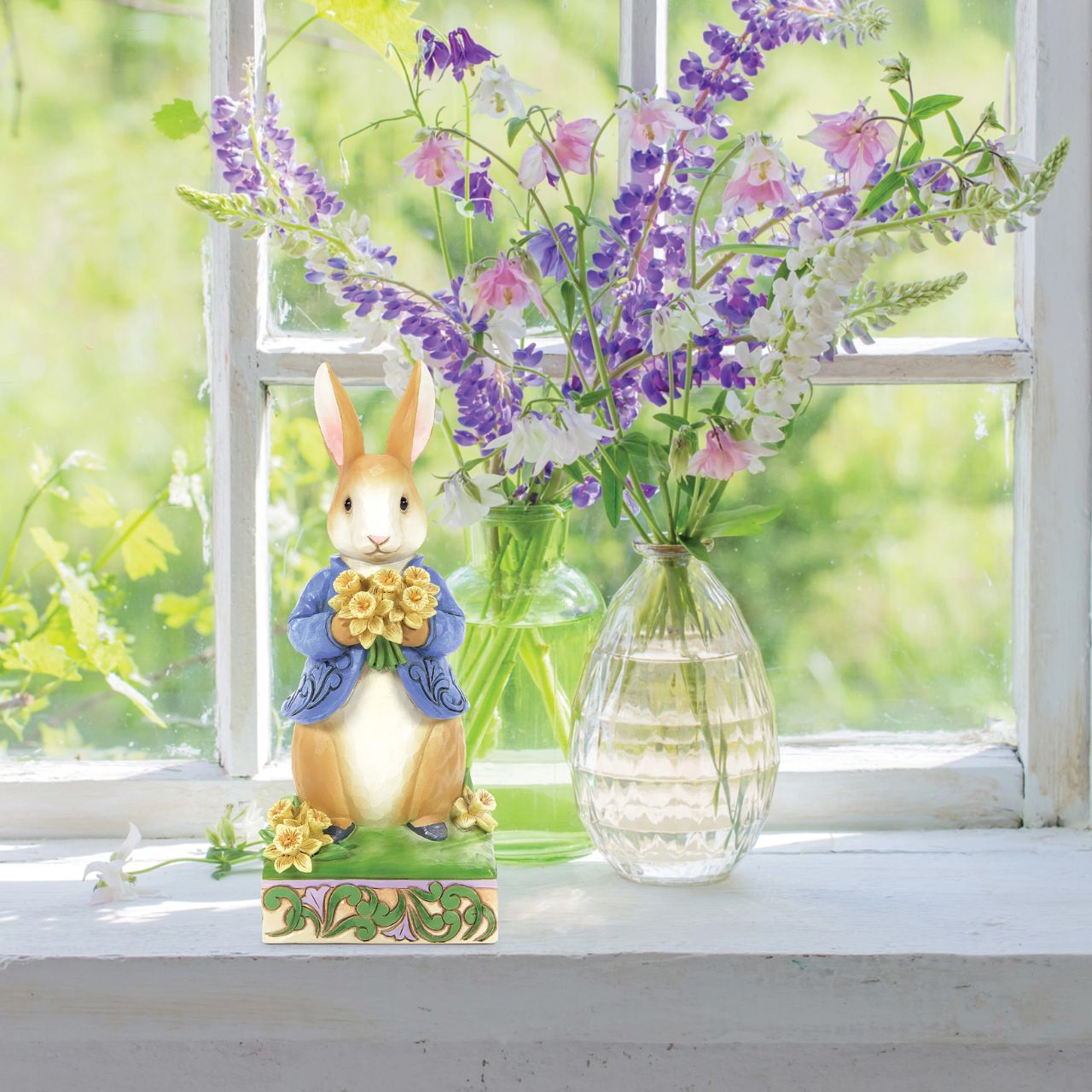 Peter Rabbit with Daffodils - Wearing his signature blue coat, Peter Rabbit blushes as he presents a bouquet of daffodils picked for you in this sweet design. Styled by Jim Shore, Peter's coat boasts rosemale petals as he stands on a decorated stage of springtime growth.