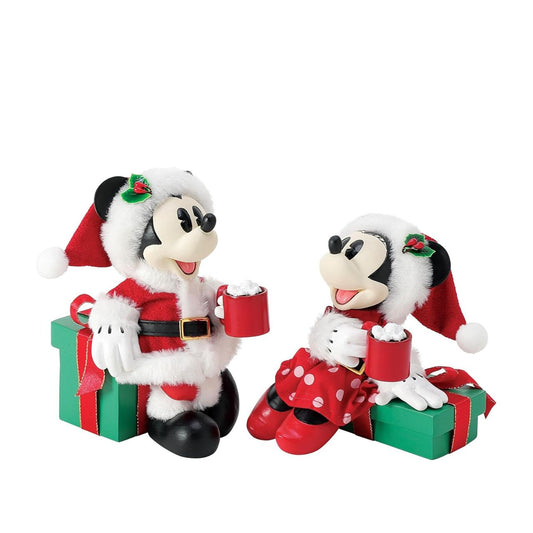 Capture the magic of the season with this charming Department 56 Disney figurine. Mickey and Minnie Mouse are nestled together on festive wrapped gifts, each cradling a steaming mug of hot cocoa—the perfect scene of cosy holiday togetherness.