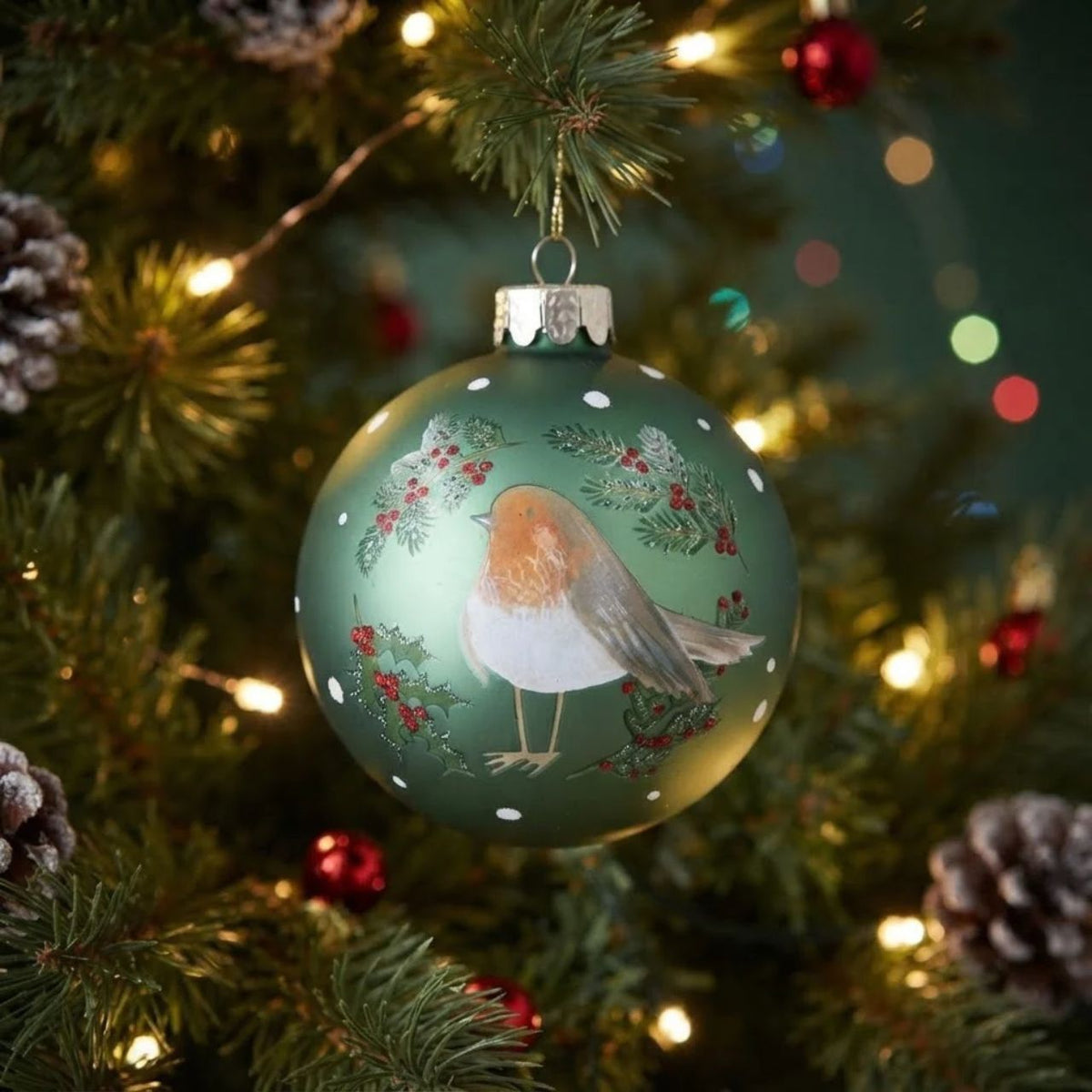 Gisela Graham Robin with Berry Sprigs Green Christmas Glass Bauble brings festive charm to your tree. This hand-finished ornament features a detailed robin perched among delicate berry sprigs in rich green tones, capturing the beauty of winter wildlife.