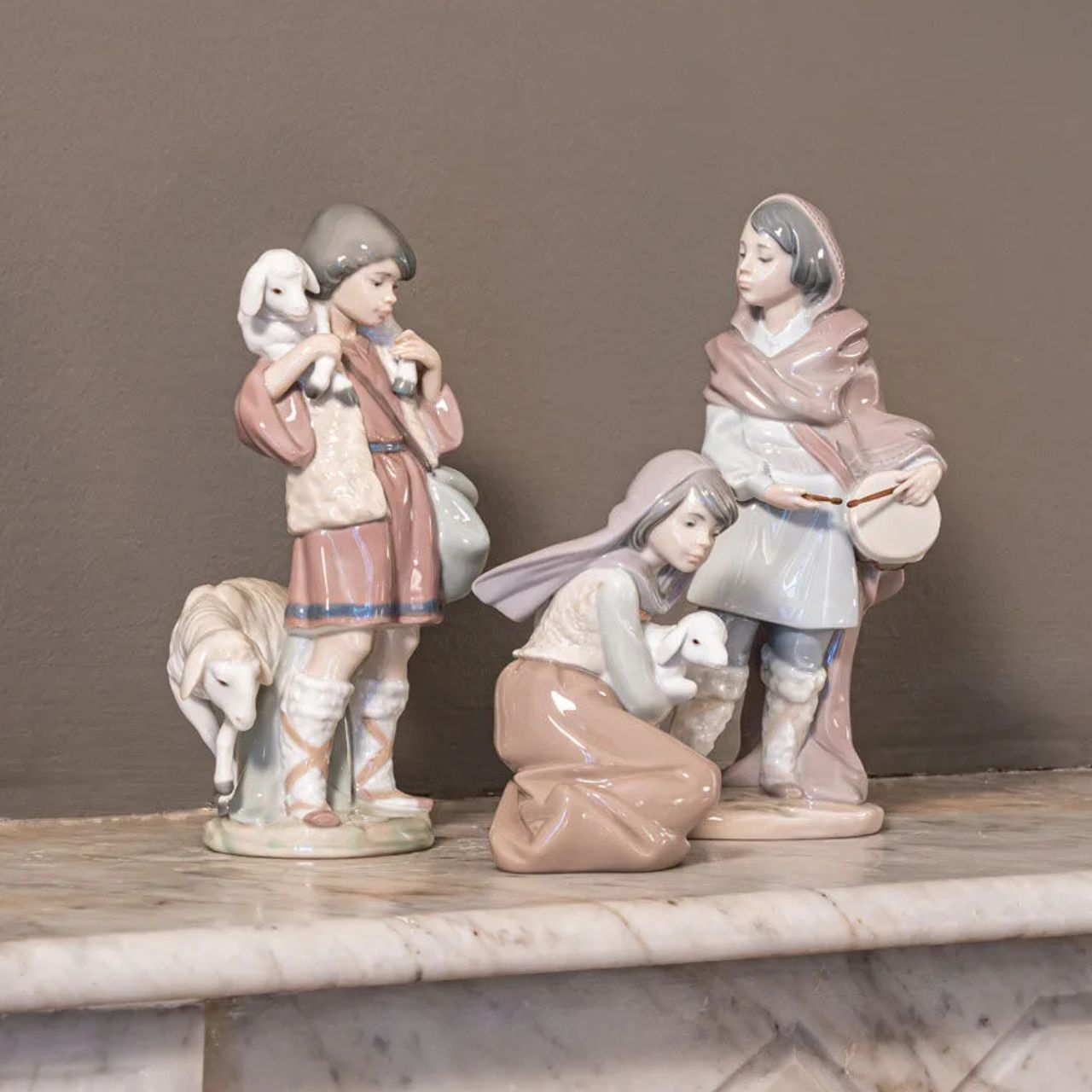 A young shepherd comes to worship the newborn Child Jesus, with a lamb on his shoulders and another close to his legs. It is part of a group of pieces that form a complete Nativity scene, the most important scene for all Christians in the world. It is a glossy porcelain piece decorated with Lladró's classic pastel color palette, a set designed to create a warm and welcoming atmosphere in the home during the family days of Christmas.