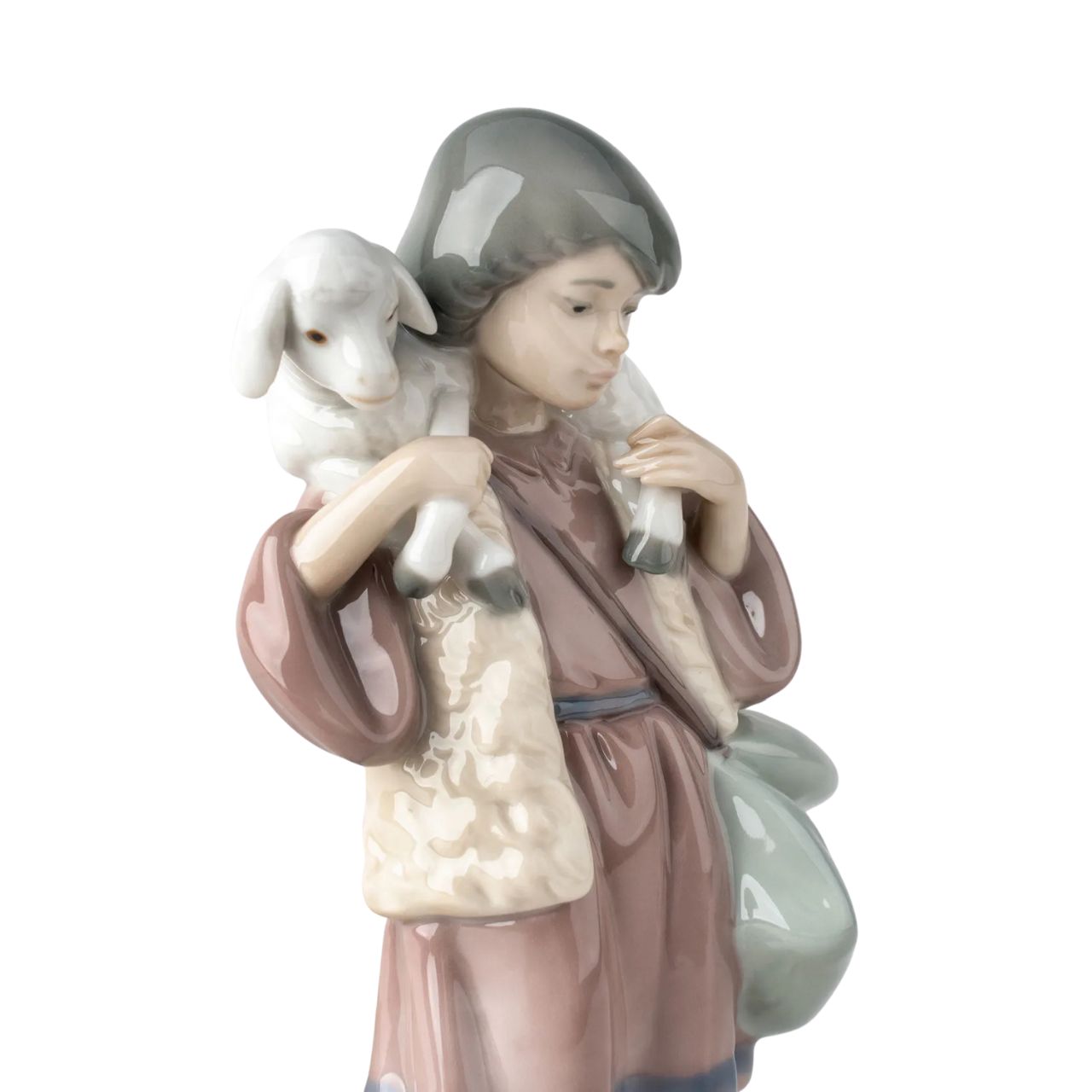 A young shepherd comes to worship the newborn Child Jesus, with a lamb on his shoulders and another close to his legs. It is part of a group of pieces that form a complete Nativity scene, the most important scene for all Christians in the world. It is a glossy porcelain piece decorated with Lladró's classic pastel color palette, a set designed to create a warm and welcoming atmosphere in the home during the family days of Christmas.