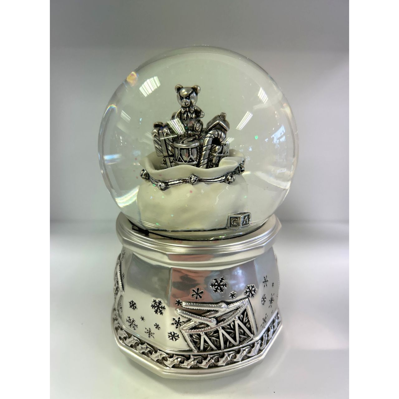 Silver coloured 100 mm snow globe with gift bag. After being wound up, the presents spin in the bag, going up and down and a Christmas melody sounds.