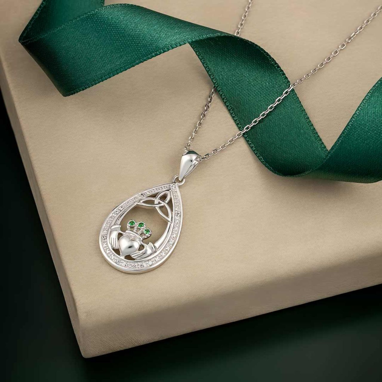 This beautiful sterling silver necklace features our two most popular symbols - the Claddagh and the Trinity knot. Our designers have created a piece in a teardrop shape accented by cubic zirconia and 3 green crystals on the Claddagh's crown.