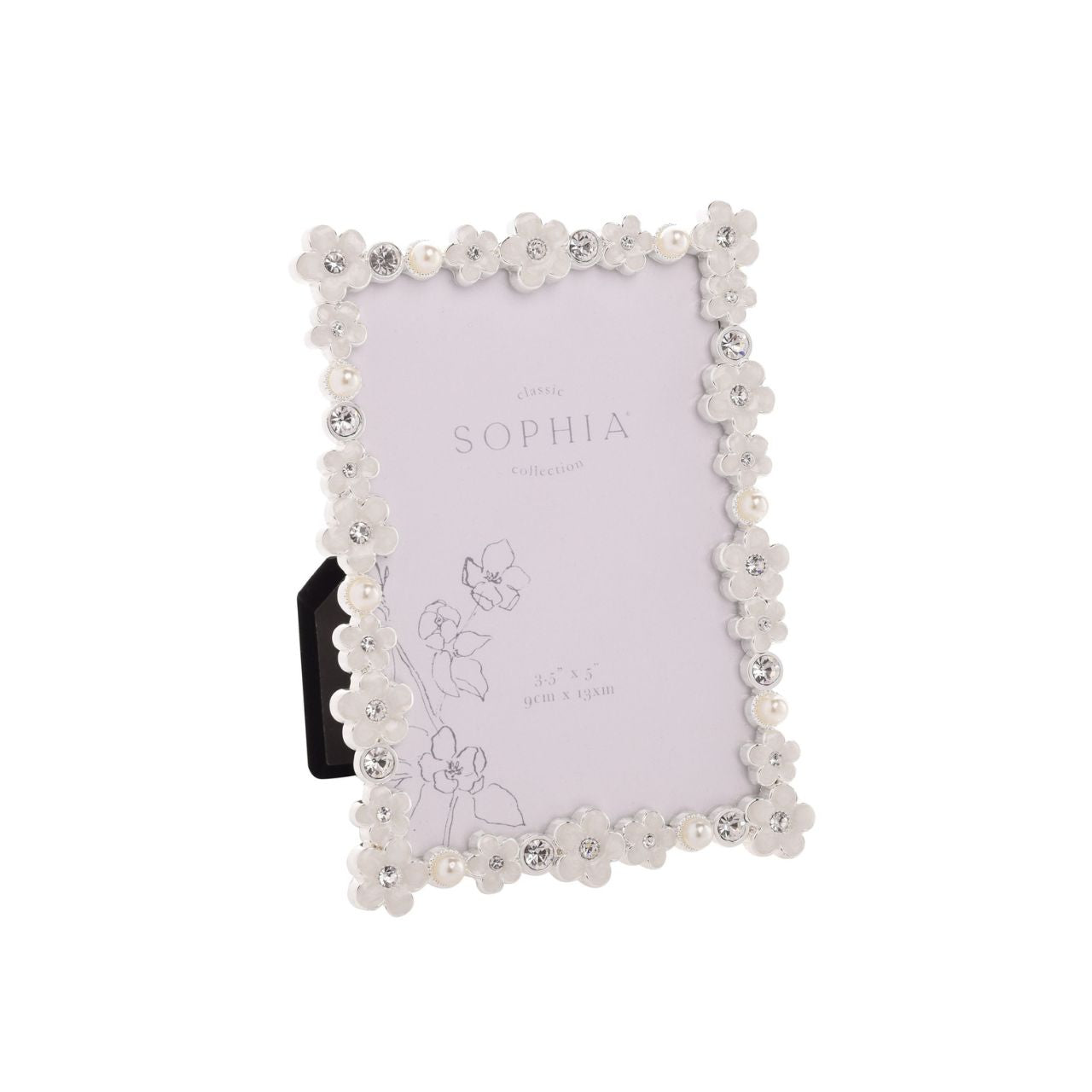 Introduce a touch of elegance and charm to your photo collection with the Sophia Classic Daisy 3.5” x 5” Frame in White. Featuring an intricate floral pattern and decorative crystals, this frame transforms your cherished memories into a stunning display piece that exudes sophistication.
