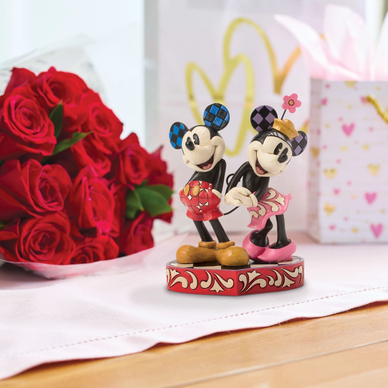 This romantic Disney design by Jim Shore features Mickey and Minnie Mouse, adorned with rosemaling and patchwork details. They stand on a heart-shaped base radiating the warmth of their timeless affection.
