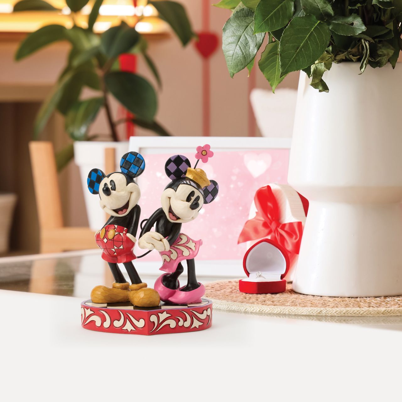This romantic Disney design by Jim Shore features Mickey and Minnie Mouse, adorned with rosemaling and patchwork details. They stand on a heart-shaped base radiating the warmth of their timeless affection.