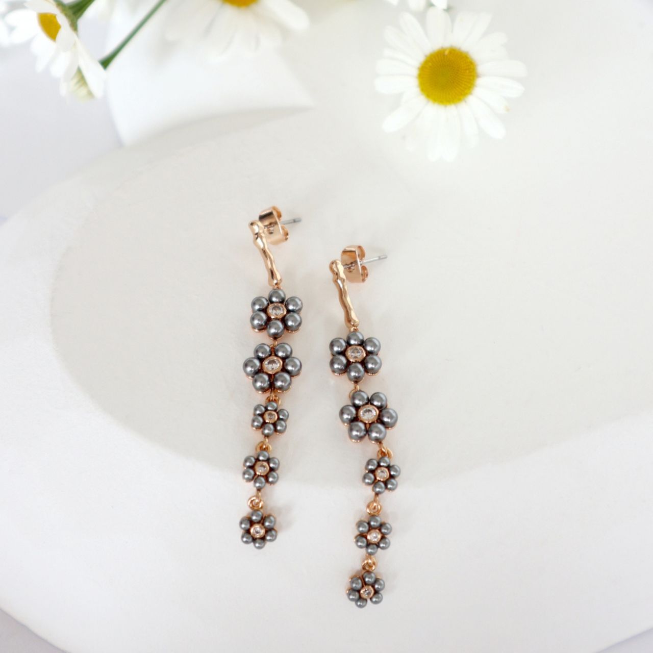 Graceful and eye-catching, the Daisy Grey Pearl Drop Earrings capture the beauty of blossoms in full bloom. Inspired by the delicate charm of daisies, these earrings bring a feminine yet modern touch to your jewellery collection.