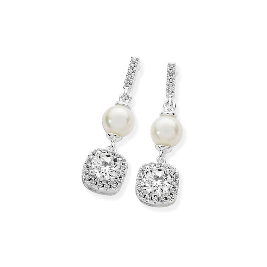 These earrings add an element of glamour to any outfit. Fashioned in silver, a beautiful white pearl suspends from a sparkling crystal lined linear bale stud. From this, a dazzling clear, round crystal in a four prong mount is set in a cushion shaped drop which has been encrusted with micro crystals. These drop earrings are 25mm in length. Full of sparkle and enchantment, these earrings are secured with push back closures.