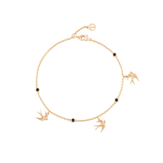 The Swallow Bracelet 3 Swallows &amp; Black CZ - Gold is a stunning piece that captures the essence of freedom and grace. This bracelet features three elegantly flying swallows, symbolizing the spirit of adventure and new beginnings. The intricate design, enhanced with black CZ crystals, adds a radiant touch of sophistication and sparkle.