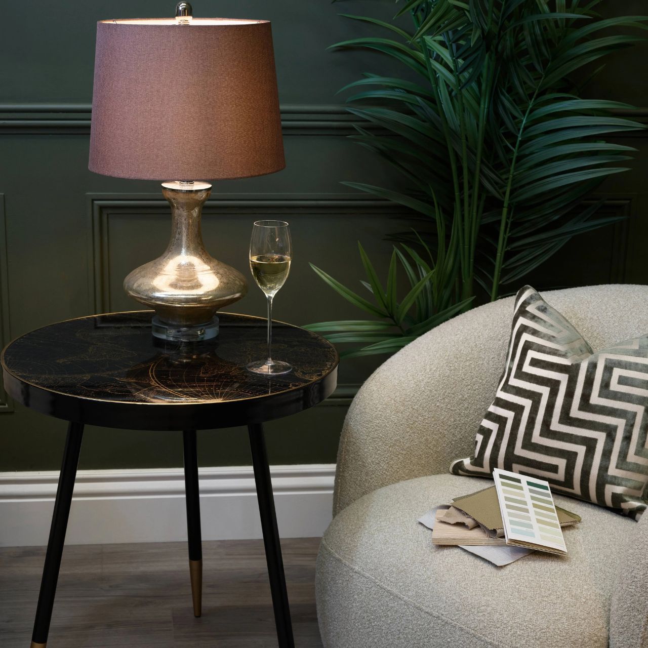 This side table features a black painted frame with a gold tipped leg, paired with a striking black and antiqued gold world map patterned top finished with an acrylic overlay. The detailed design adds depth and character while creating a refined, decorative surface.