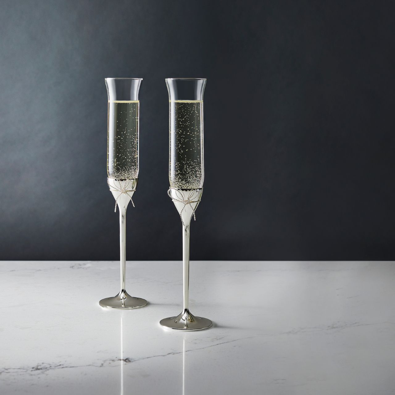 Wedgwood Vera Wang Love Knots Toasting Flutes Pair  Beautiful sterling silver Love Knots characterize the elegant Vera Wang Love Knots collection. A slender profile of fine crystal is offset by a silver-plated base accented with a delicate bow. Raise a toast with these elegant Love Knots Toasting Flutes.