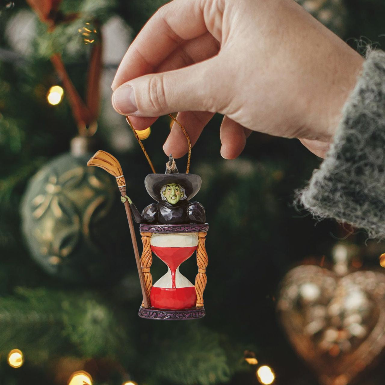 Someone looks unhappy in this hourglass ornament. As the sands of time fall, the Wicked Witch frowns knowing it's only a matter of time until good wins the day. Place this green-faced miscreant into your tree and watch her moments before melting.