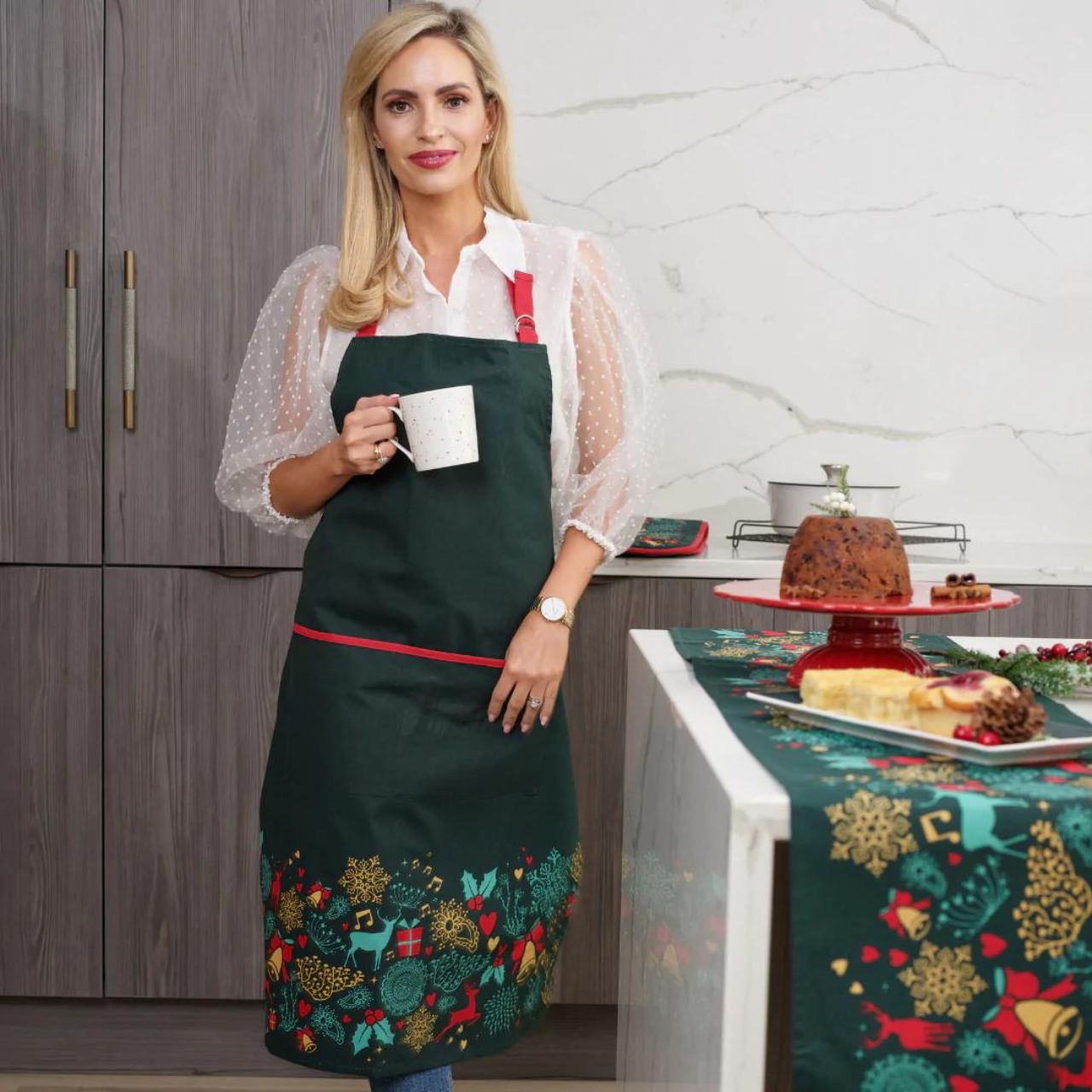 A Christmas Wish Apron by Mindy Brownes Interiors  A beautiful apron finished in forest green with a Christmas design that depicts some of Christmas' key elements, such as reindeer, presents, music notes, and more.  A stylish, yet practical way to avoid any outfit mishaps while baking and cooking this Christmas season.
