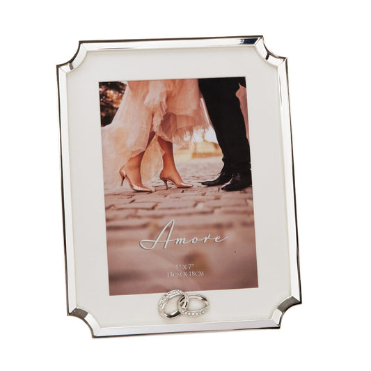 AMORE BY JULIANA® Silver Scalloped Corner Frame 5" x 7"  A beautiful silver plated cut corner 5" x 7" (13x18cm) photo frame. The frame features an intertwined silverplated crystal ring icon, a crisp white mount and a standing strut.