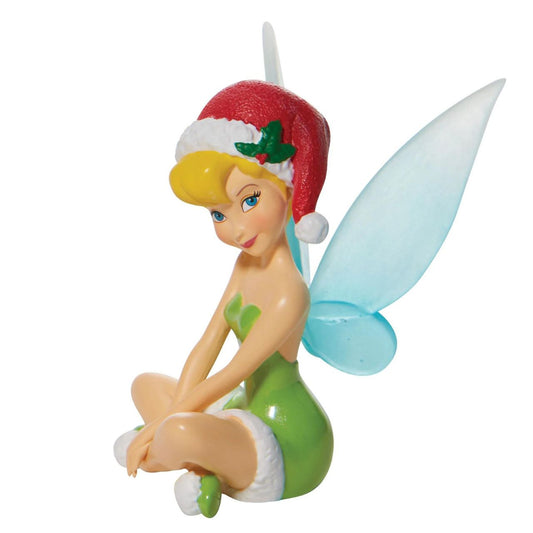Christmas Tinker Bell Figurine Department 56  Tinker Bell dons her most festive dress this winter to celebrate Christmas in style. Outfitted in fur to match her Santa hat, she sits pretty and pleasantly in this graceful miniature. With pixie dust and holly, she personifies jolly. 
