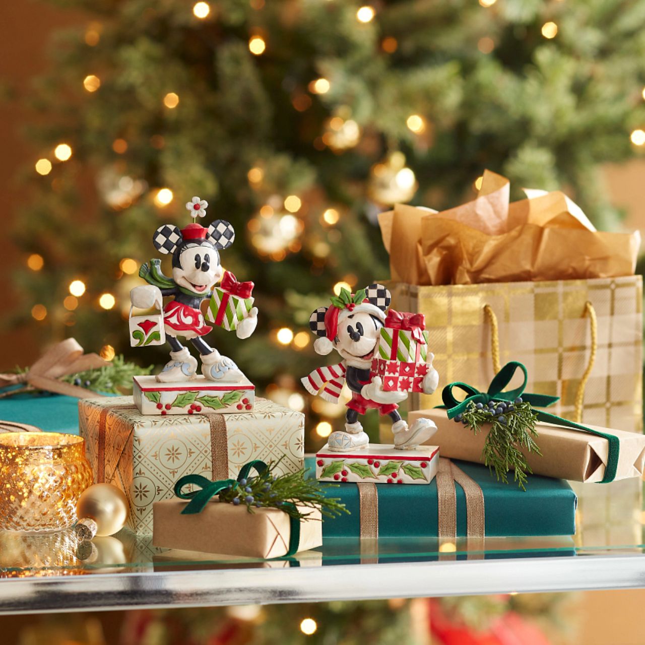 Jim Shore Christmas Mickey with Stack of Presents Figurine  Disney comes home for the holidays with this festive figurine by Jim Shore. Donning a candy cane striped scarf, Mickey wears a neighborly smile as he carries a towering stack of presents. The cheerful mouse boasts a holly brimmed Santa hat.