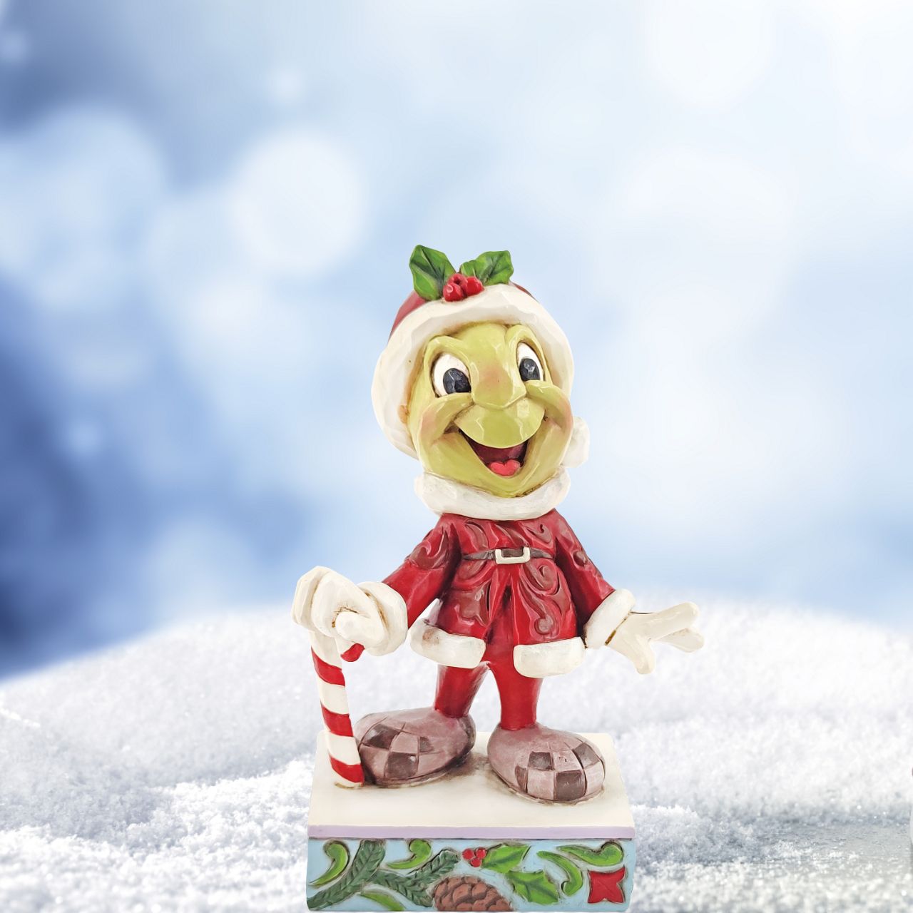 Jim Shore Disney Traditions Christmas Jiminy Cricket Figurine  Be Wise and Be Merry  This year, Jiminy Cricket lets Christmas be his guide. Donning Santa's coat and boots the charming little insect hopes to turn all your wishes true this season. Walking with a candy cane, the cricket smiles brightly in this Jim Shore classic.