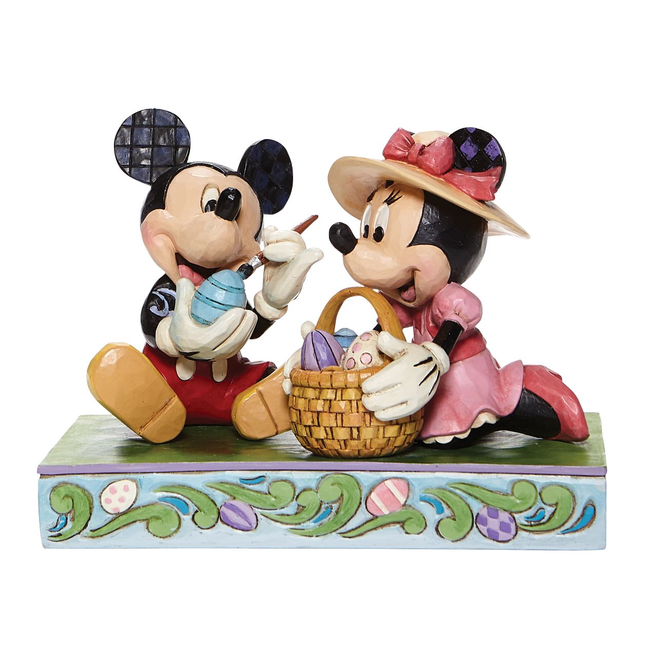 Jim Shore Easter Artistry - Mickey and Minnie Easter Figurine  In this joyful scene, Mickey and his sweetheart Minnie, are filled with excitement as they perfect their eggs for an egg hunt. Brighten up your collection with this vibrantly, colorful Easter piece by Jim Shore.