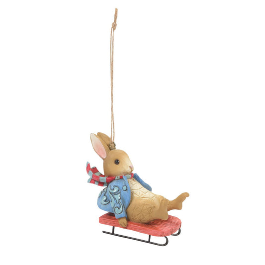 Jim Shore Peter Rabbit Sledging Hanging Ornament  This charming Peter Rabbit hanging ornament will make the perfect gift for any Beatrix Potter lover. Donning his classic blue jacket, the beloved rabbit is styled in beautiful Jim Shore patchwork detail around his coat, sitting on a sledge, also making it a fabulous additional Christmas decoration.