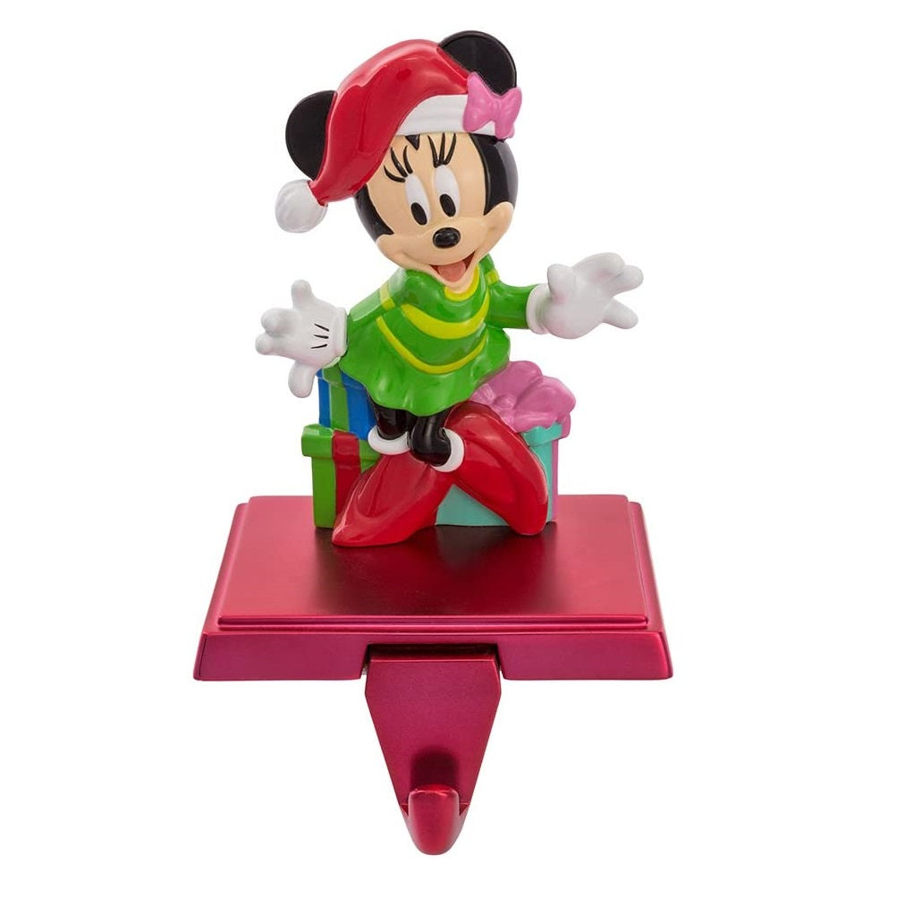 Kurt S Adler Minnie Mouse Stocking Holder  Hang up your favorite stocking this Christmas with this Disney Minnie Mouse stocking hanger from Kurt Adler. Features Minnie Mouse wearing a green dress, and a red and white Santa hat standing in front of wrapped presents.