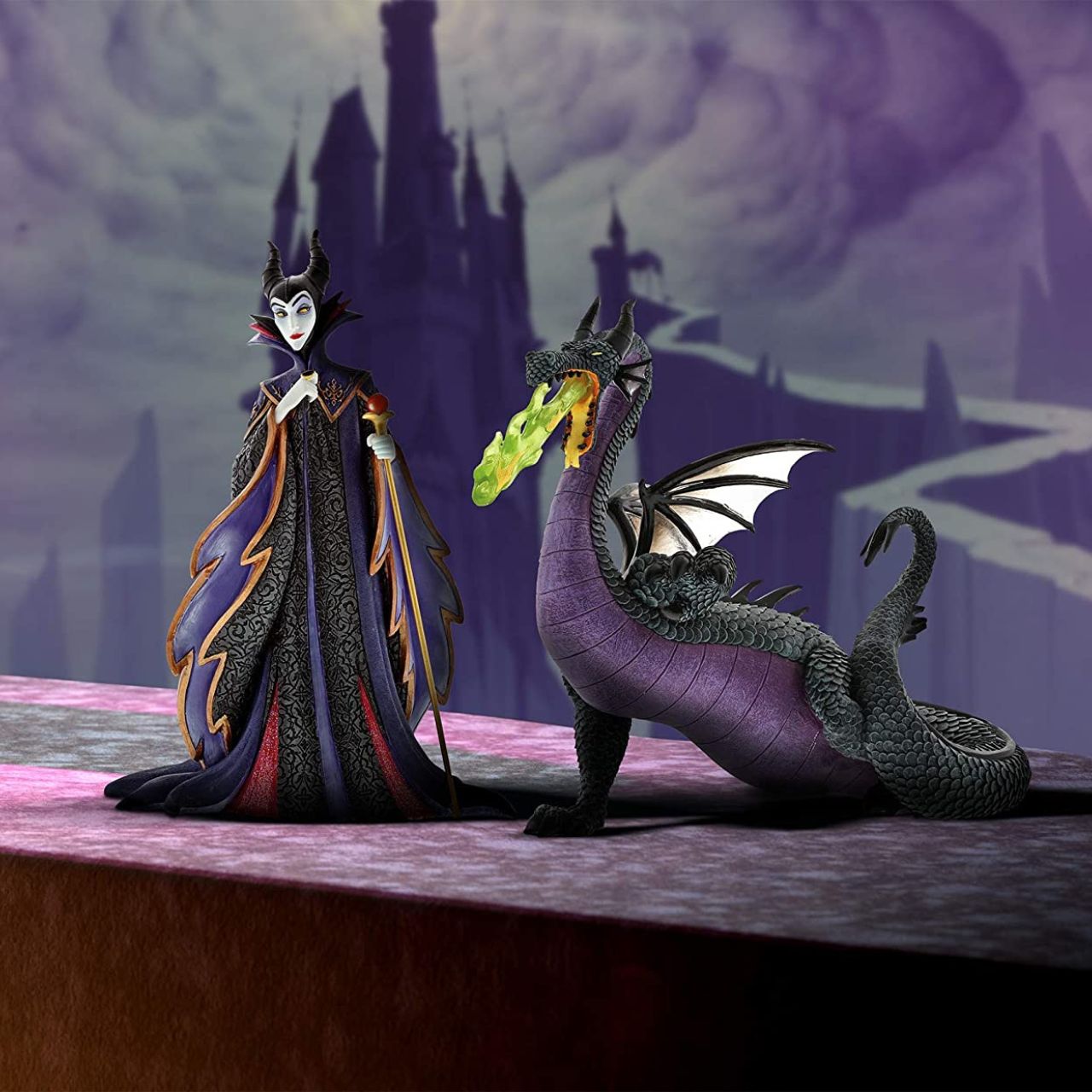 Disney Maleficent Figurine  Maleficent strikes a regal pose in this handcrafted design from the Haute Couture collection, her ominous onyx robes reimagined as a satin gown and feathered, floor-length cape. Ready to rule the runway, the fashionable figure holds a golden scepter.