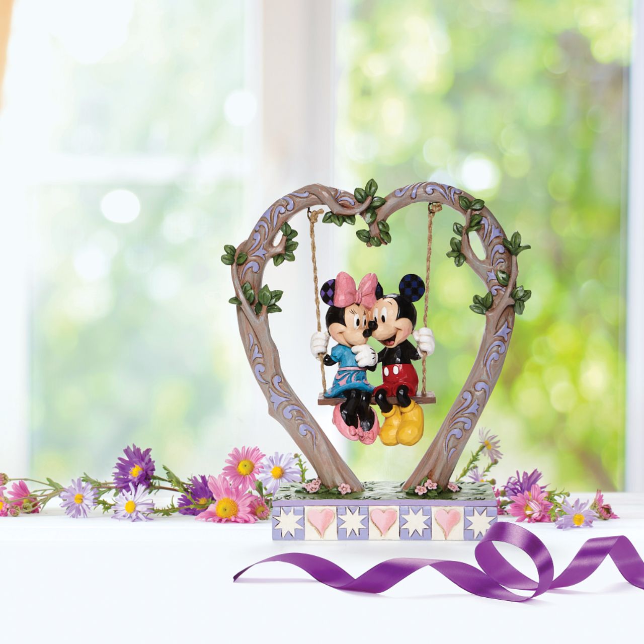 Jim Shore Sweethearts in Swing - Mickey and Minnie on Swing Figurine  Suspended from a heart-shaped branch, a smitten Mickey and Minnie swing into Spring in this quintessentially romantic Jim Shore sculpture.