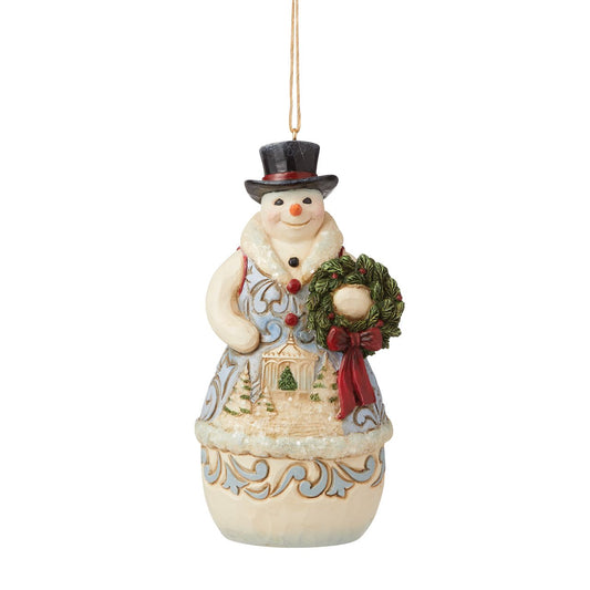 Jim Shore Heartwood Creek Victorian Christmas Snowman with Wreath Hanging Ornament  This Jim Shore Victorian snowman holds a wreath while a timeless winter scene plays across his chest. A smile on his face and a top hat on his head, he is ready for whatever the season brings. This snowman is brimmed in holly and holiday wonder.