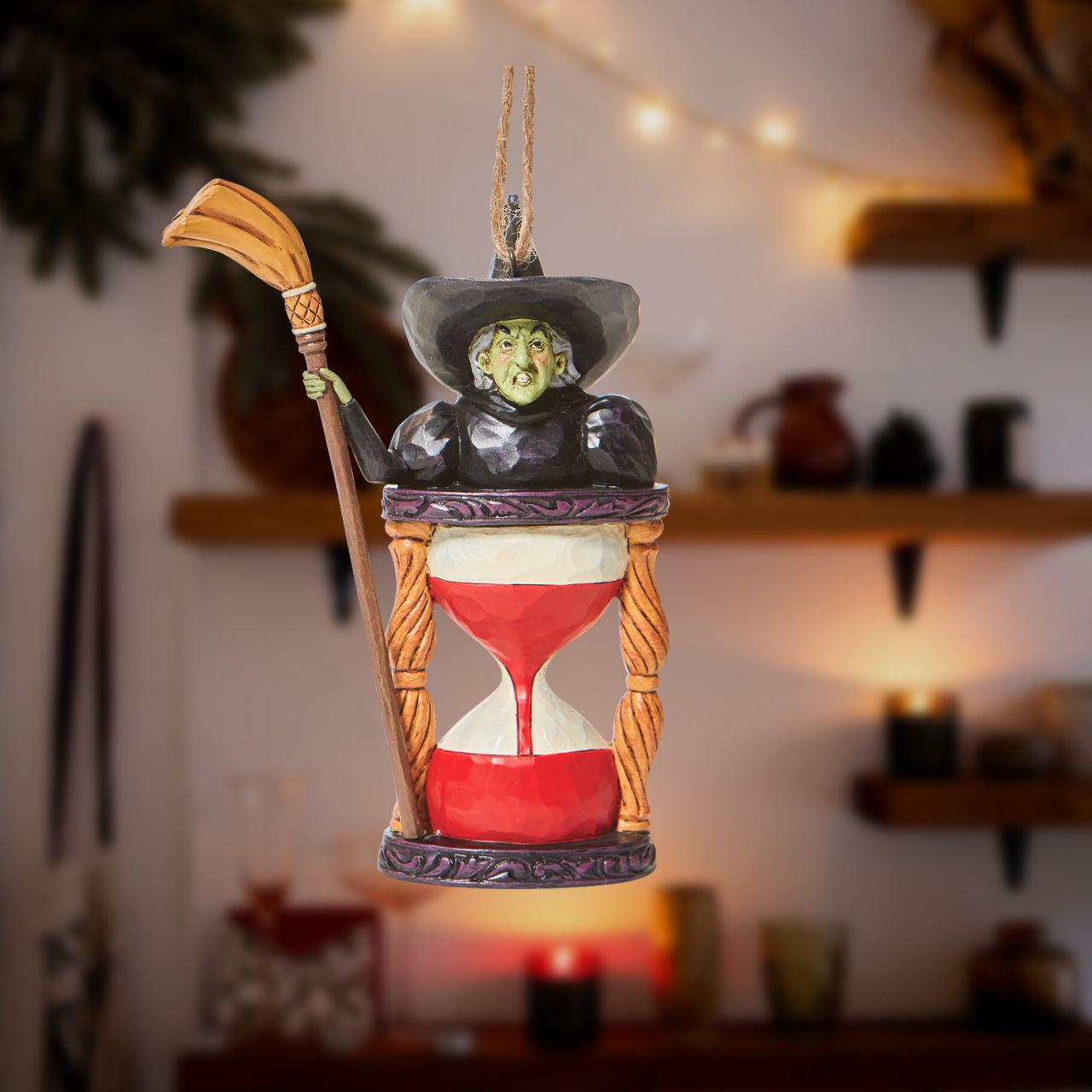 Jim Shore Wicked Witch with Hourglass Hanging Ornament  Someone looks unhappy in this hourglass ornament. As the sands of time fall, the Wicked Witch frowns knowing it's only a matter of time until good wins the day. Place this green-faced miscreant into your tree and watch her moments before melting.