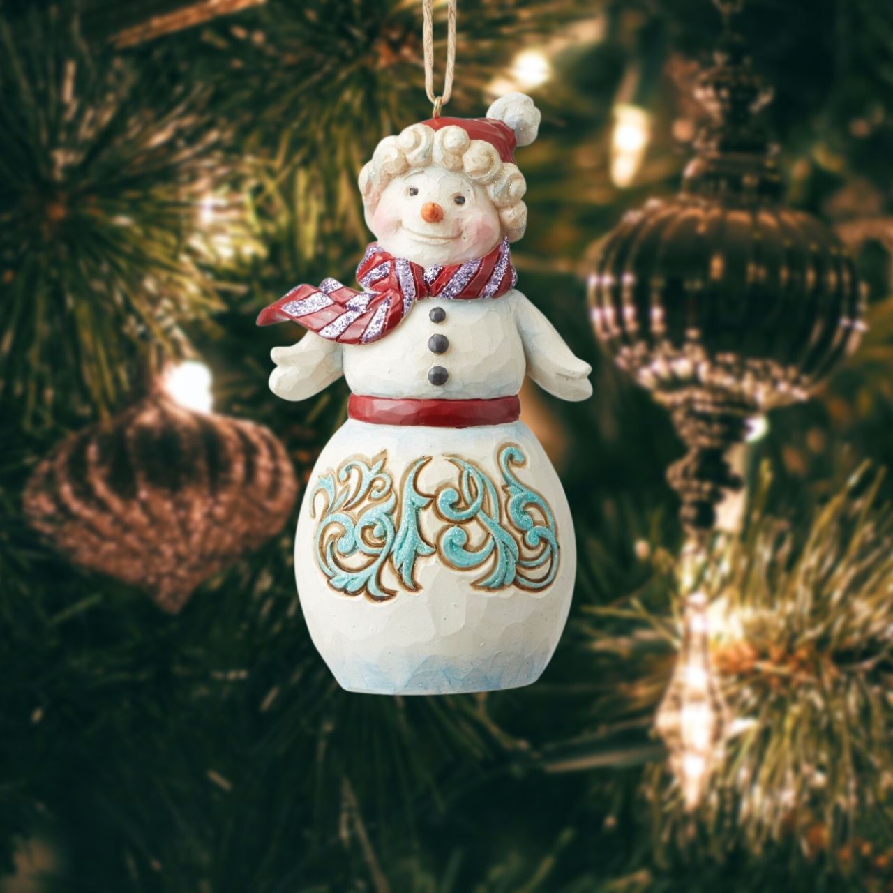 Jim Shore Heartwood Creek Winter Wonderland Snowman Hanging Ornament  Jim Shore's Winter Wonderland collection features a subtle glitter finish with Jim's signature color and intricate design. This whimsical holiday Snowman ornament with knit cap and scarf is strikingly decorated with a bold blue rosemaling motif.